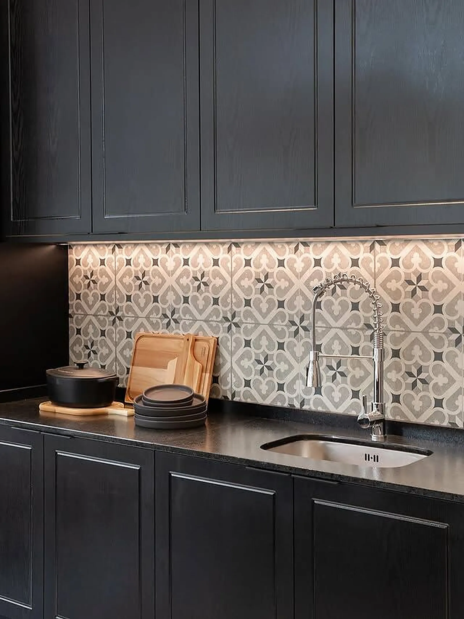Detalhe de cozinha planejada com marcenaria preta, bancada em granito e revestimento hidráulico